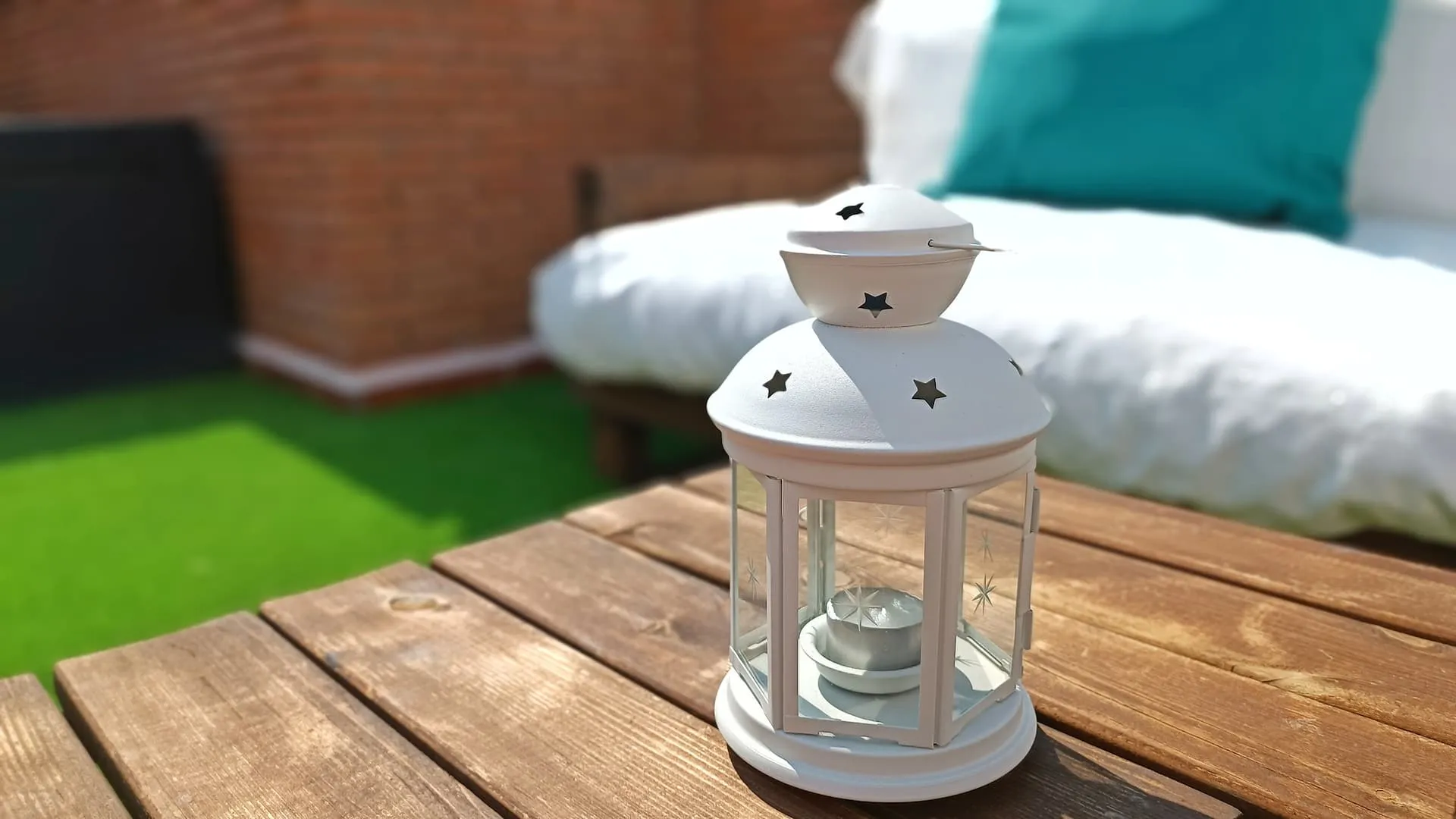 Terraza con zona césped y baúl con cojines