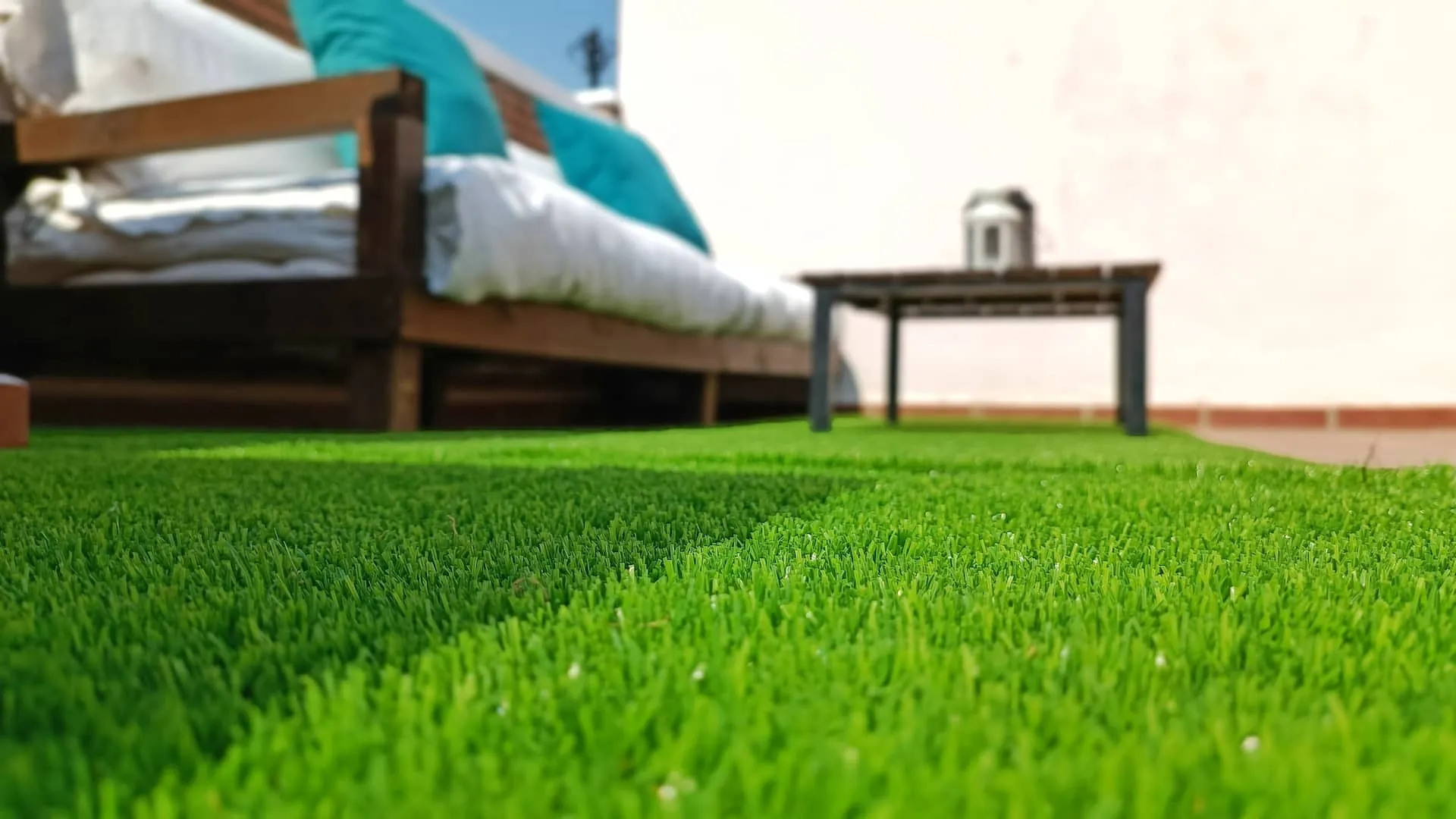 Terraza con zona césped y baúl con cojines 2